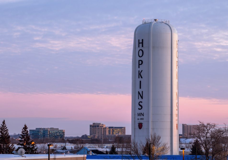 HOPKINS, MN - JANUARY 2022 - A High Angle Telephoto Shot of the Suburban Hopkins, Minnesota Water Tower and Medium Rise Building under a Pink and Blue Belt of Venus Evening Sky
